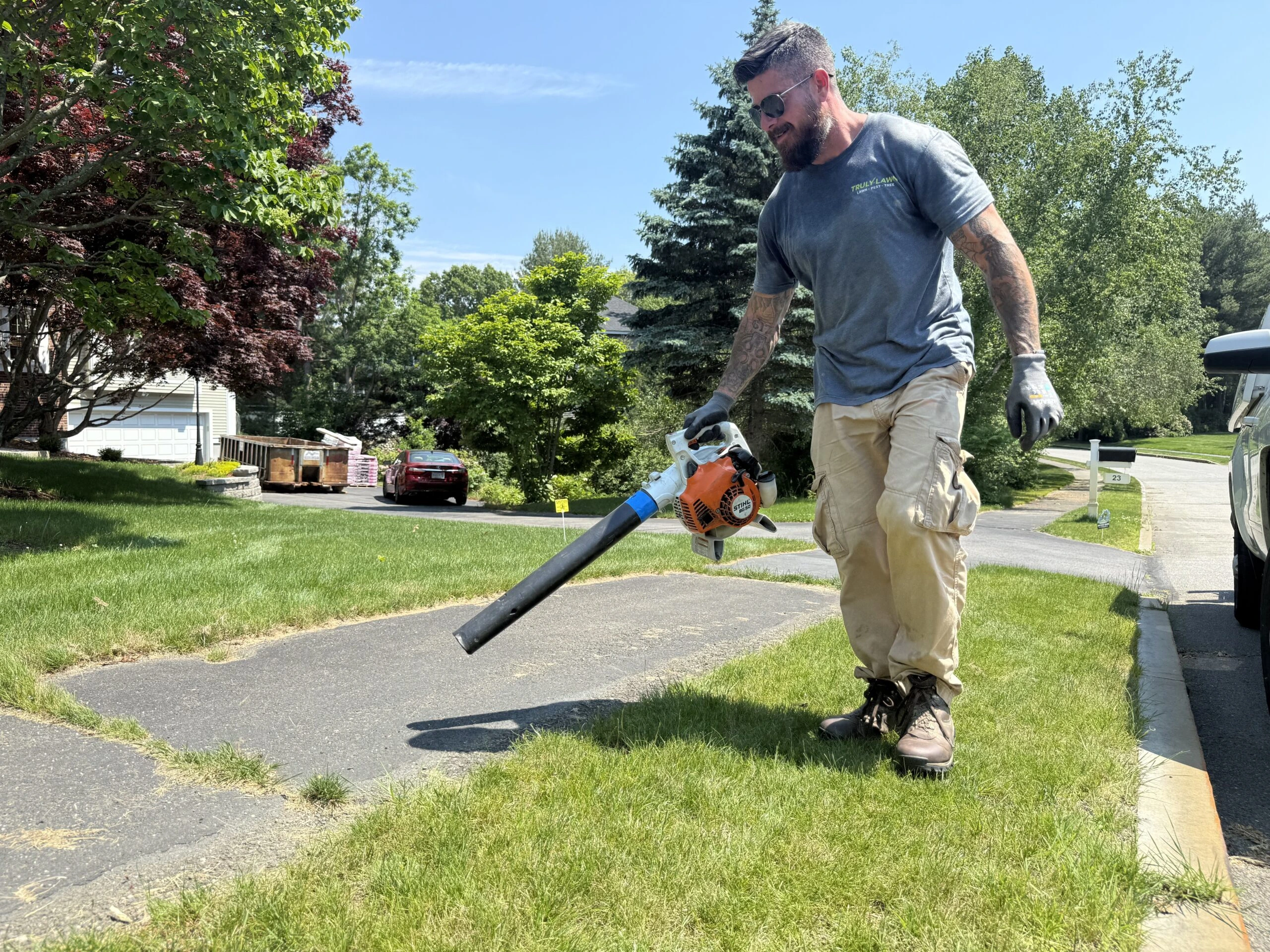 Technician clearing fertilizer off sidewalk after lawn treatment