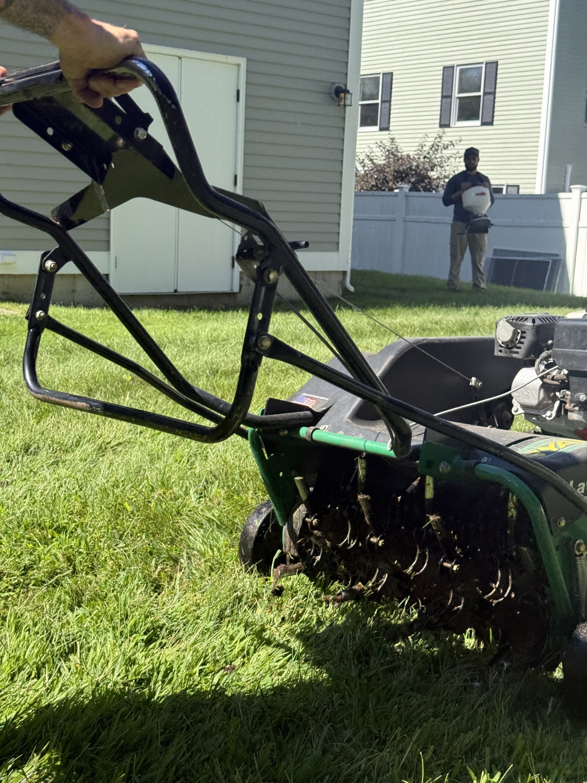 Core aeration machine treating a lawn in Massachusetts